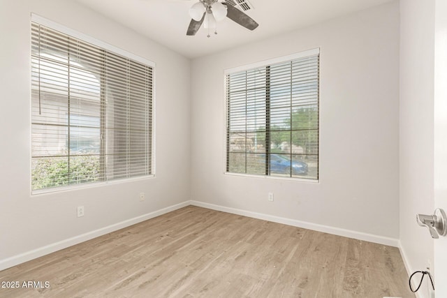 empty room featuring a ceiling fan, baseboards, visible vents, and light wood finished floors