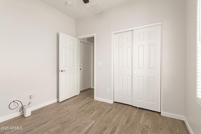 unfurnished bedroom with a closet, baseboards, visible vents, and light wood-type flooring