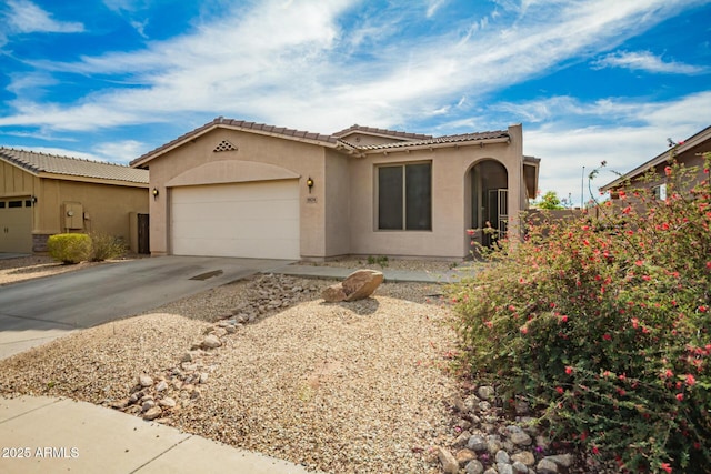 mediterranean / spanish house with a garage, stucco siding, driveway, and a tile roof