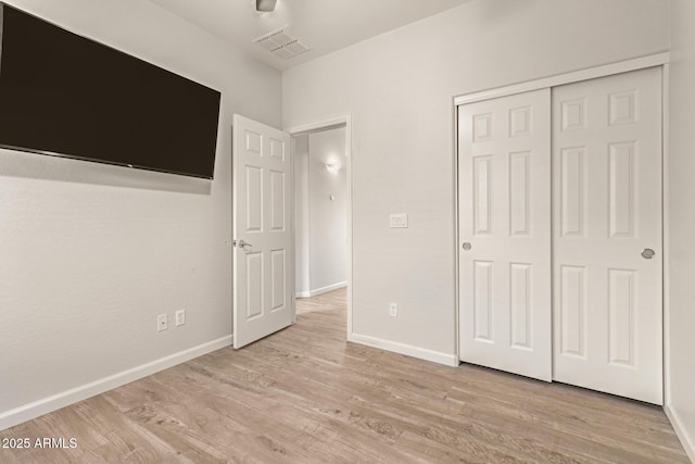 unfurnished bedroom featuring a closet, baseboards, visible vents, and light wood-type flooring