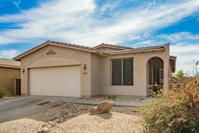 mediterranean / spanish house with a garage, stucco siding, driveway, and a tile roof