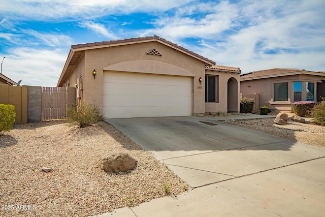 mediterranean / spanish house featuring an attached garage, stucco siding, a gate, a tiled roof, and driveway
