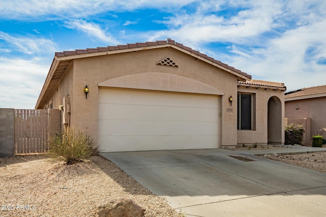 view of front facade with a garage, fence, stucco siding, a tiled roof, and concrete driveway