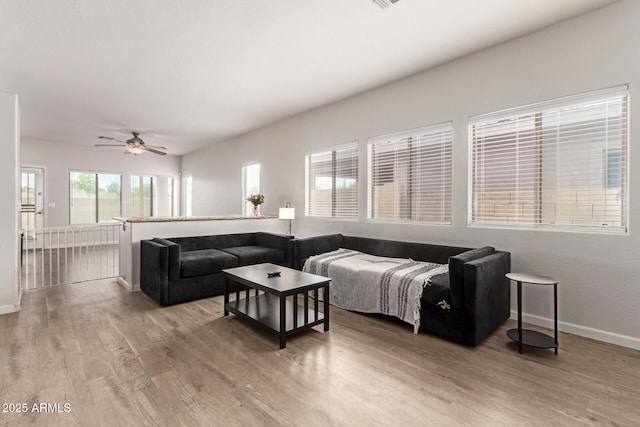 living room with baseboards, ceiling fan, and light wood-type flooring