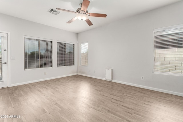 empty room with visible vents, light wood-style floors, ceiling fan, and baseboards