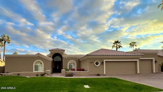 mediterranean / spanish home featuring a front yard and a garage