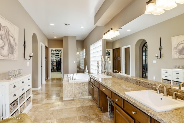 bathroom featuring tiled tub and vanity