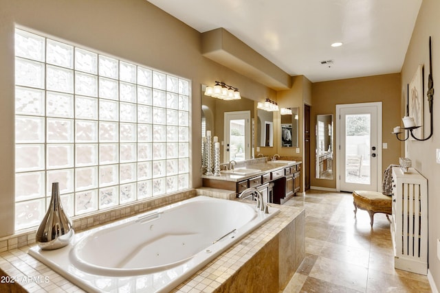 bathroom with vanity, a wealth of natural light, and tiled tub