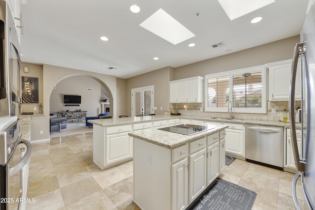 kitchen featuring light stone countertops, stainless steel dishwasher, black electric cooktop, white cabinets, and a center island