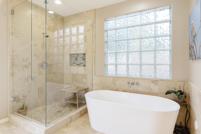 bathroom featuring tile patterned floors, plenty of natural light, tile walls, and plus walk in shower