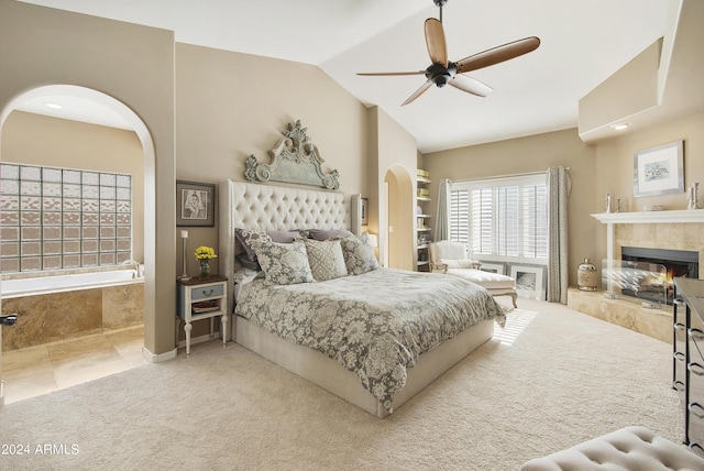 carpeted bedroom with a tile fireplace, ceiling fan, and lofted ceiling