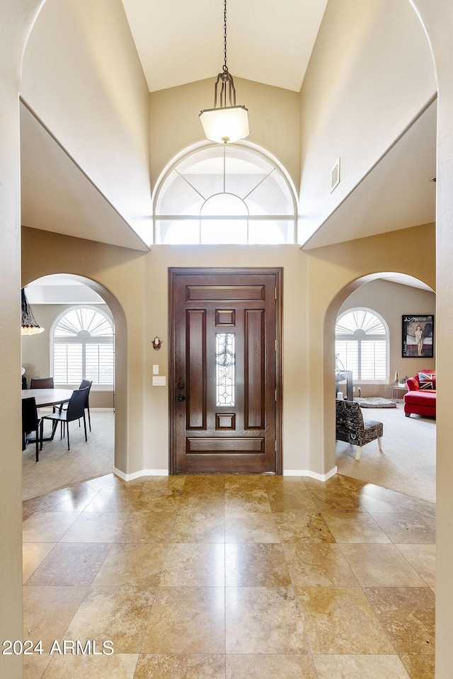 foyer entrance with light carpet, plenty of natural light, and a towering ceiling