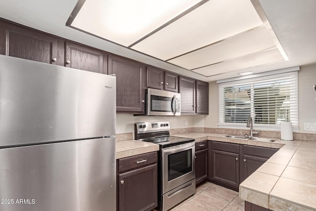 kitchen featuring appliances with stainless steel finishes, a sink, and dark brown cabinets