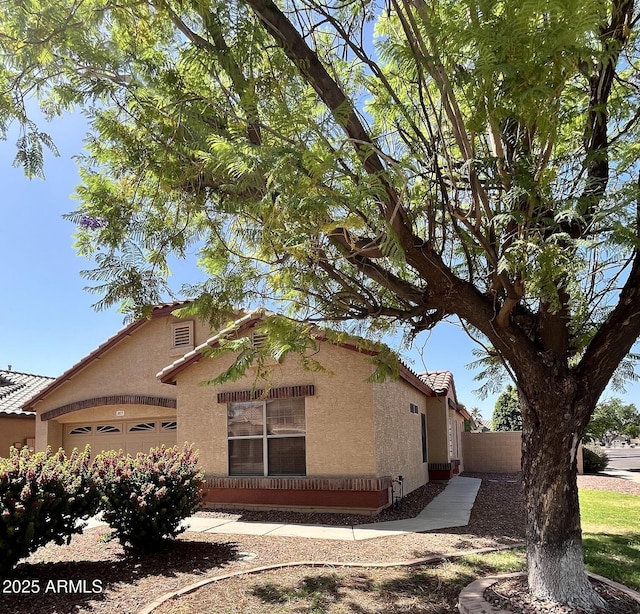 1827 E Carla Vista Dr, Gilbert, AZ 85295 - view of side of home with stucco siding, an attached garage, a tile roof, and fence