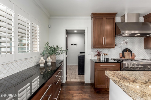 kitchen featuring wall chimney exhaust hood, light stone counters, decorative backsplash, high end stainless steel range, and ornamental molding