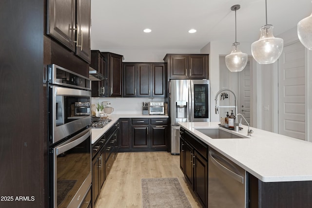 kitchen with extractor fan, light countertops, light wood-style flooring, stainless steel appliances, and a sink