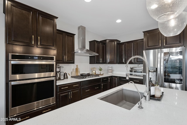 kitchen with appliances with stainless steel finishes, light stone countertops, wall chimney exhaust hood, and a sink