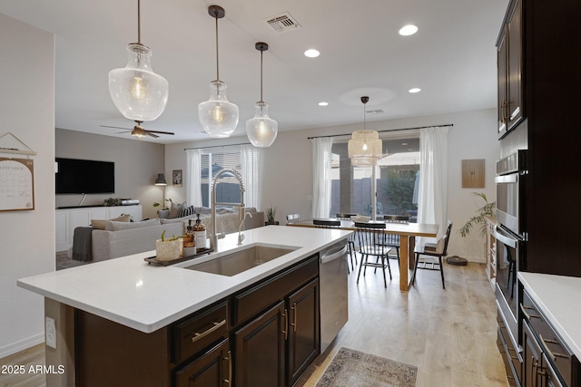 kitchen featuring visible vents, a sink, stainless steel appliances, light wood-style floors, and light countertops