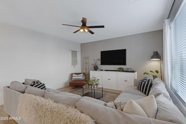 living room with baseboards, light wood-style floors, and a ceiling fan