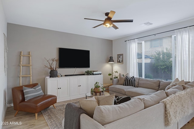 living area with visible vents, light wood-style flooring, and a ceiling fan