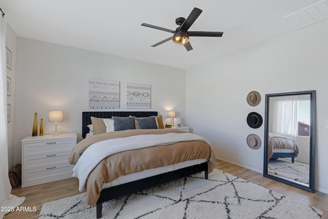 bedroom featuring light wood-type flooring, visible vents, baseboards, and ceiling fan