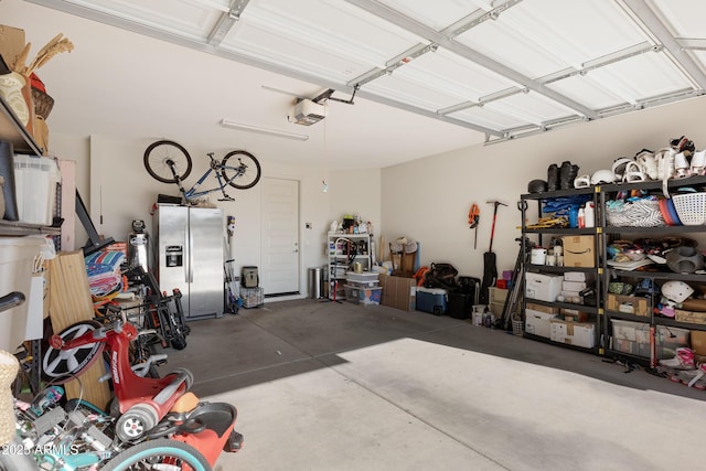 garage with a garage door opener and stainless steel refrigerator with ice dispenser