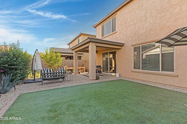 rear view of house with a patio area, stucco siding, a yard, and fence