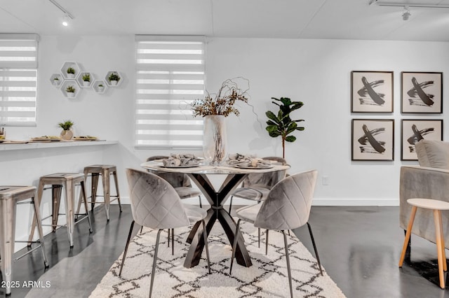 dining room with plenty of natural light, concrete flooring, and track lighting