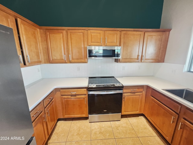 kitchen with sink, light tile patterned floors, and appliances with stainless steel finishes