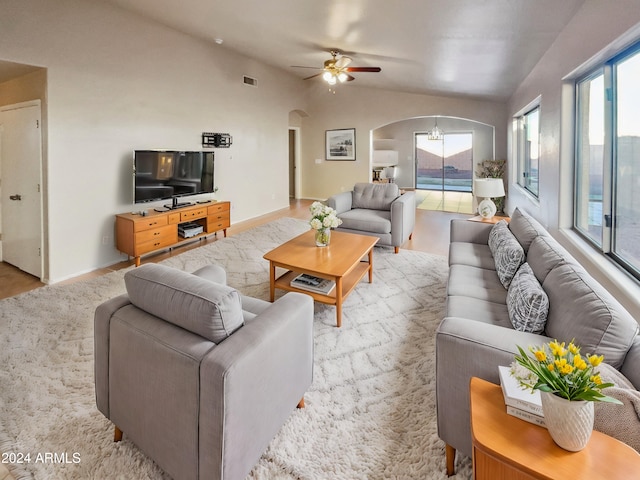 living room with ceiling fan, a healthy amount of sunlight, vaulted ceiling, and light wood-type flooring