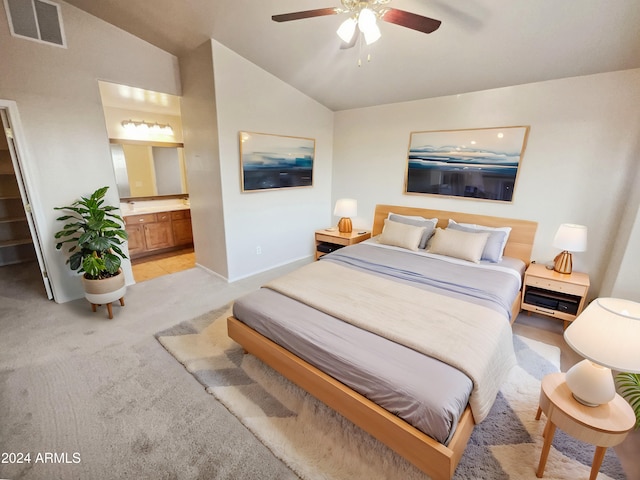 carpeted bedroom with ensuite bath, ceiling fan, and vaulted ceiling