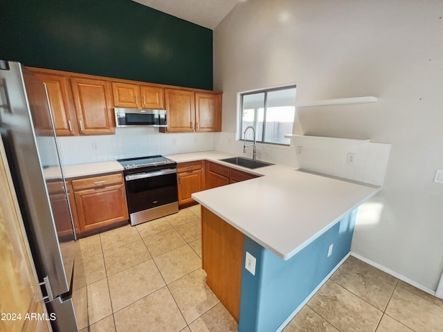 kitchen with sink, high vaulted ceiling, kitchen peninsula, light tile patterned flooring, and appliances with stainless steel finishes