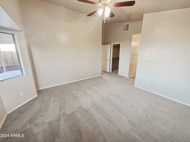 carpeted spare room with ceiling fan and high vaulted ceiling