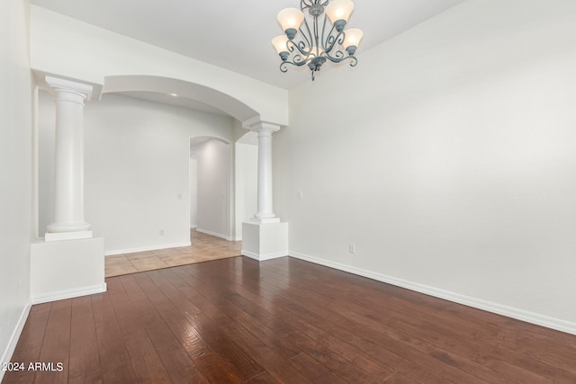 empty room with an inviting chandelier, hardwood / wood-style flooring, and ornate columns