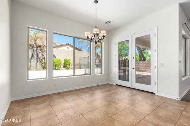 unfurnished dining area featuring french doors, a chandelier, and light tile patterned floors