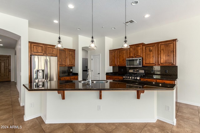 kitchen with appliances with stainless steel finishes, a breakfast bar area, pendant lighting, and a spacious island