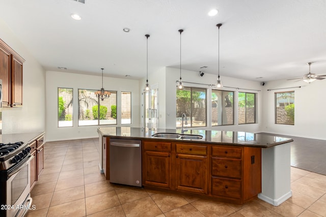 kitchen with sink, a kitchen island with sink, plenty of natural light, stainless steel appliances, and ceiling fan with notable chandelier