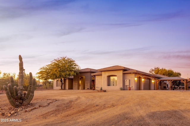 view of front of property featuring an attached garage, dirt driveway, and stucco siding