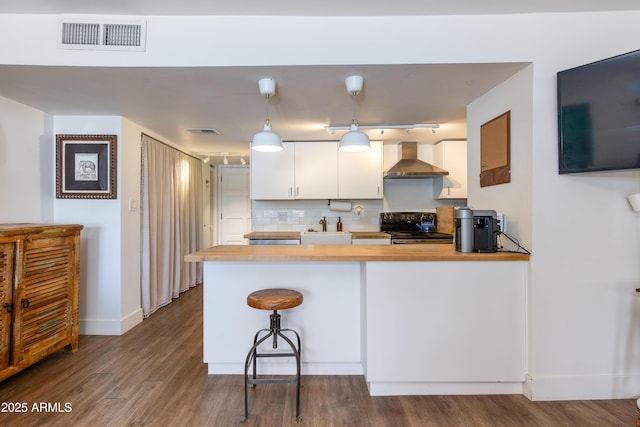 4727 E Lafayette Blvd Unit 211, Phoenix, AZ 85018 - kitchen with electric range, wall chimney exhaust hood, white cabinetry, a peninsula, and dark wood finished floors