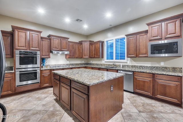 19414 W Pasadena Ave, Litchfield Park, AZ 85340 - kitchen featuring appliances with stainless steel finishes, a sink, a center island, under cabinet range hood, and light stone countertops