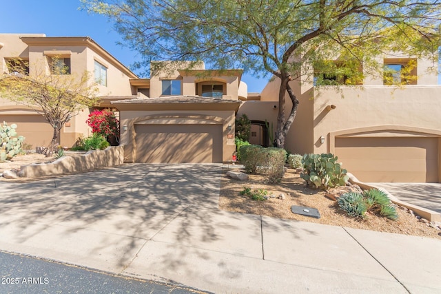 southwest-style home featuring a garage, concrete driveway, and stucco siding