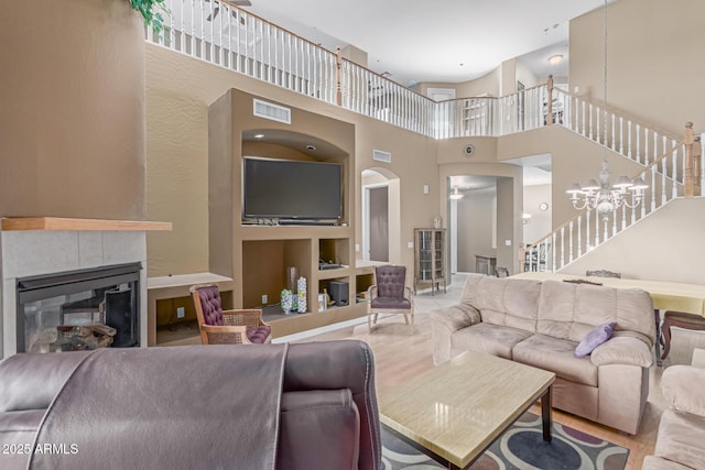 living area featuring a chandelier, stairway, a tile fireplace, and visible vents