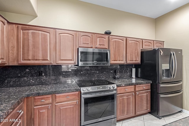 kitchen with tile countertops, light tile patterned floors, stainless steel appliances, tasteful backsplash, and brown cabinetry