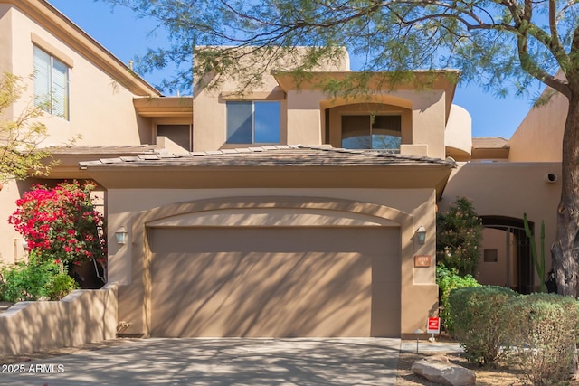 pueblo-style house featuring a garage and stucco siding