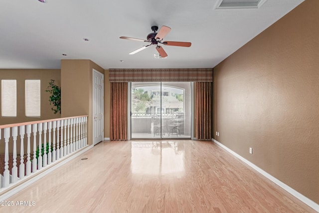 spare room with a ceiling fan, baseboards, and light wood finished floors