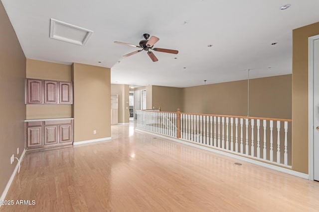 spare room featuring a ceiling fan, baseboards, and light wood finished floors