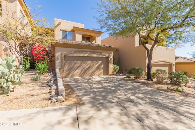 pueblo-style house with a garage, driveway, and stucco siding