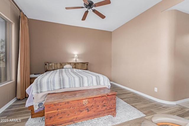 bedroom with a ceiling fan, baseboards, and wood finished floors