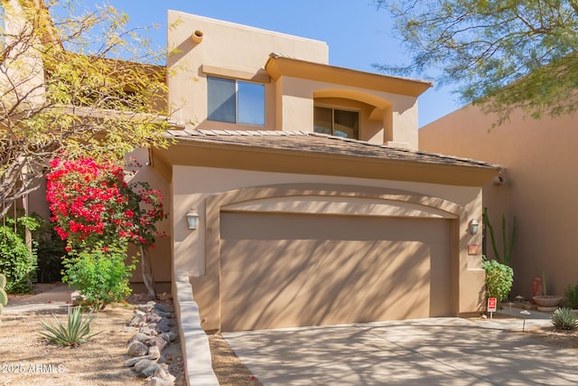 pueblo-style house with a garage, concrete driveway, and stucco siding