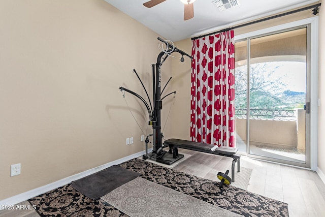 workout area featuring a ceiling fan, visible vents, baseboards, and wood finished floors